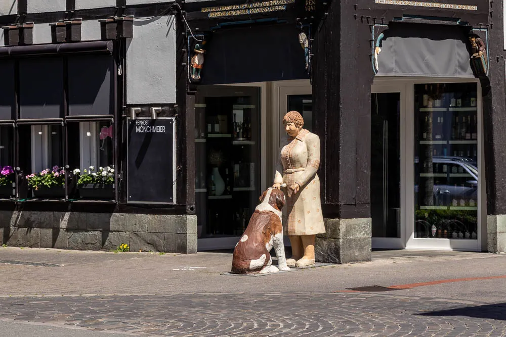 Eine Frauenfigur steht mit einem Hund vor einem Geschäft in der Altstadt von Rheda-Wiedenbrück.