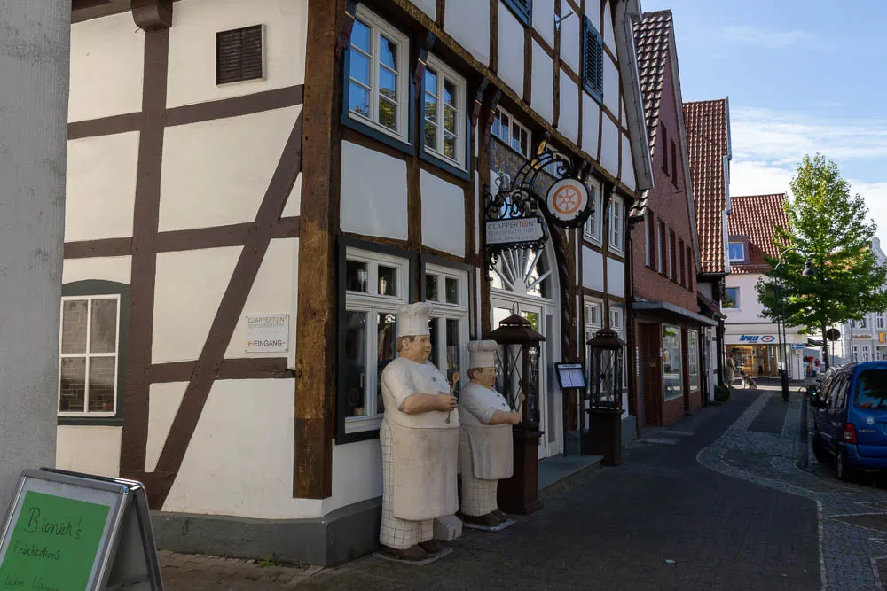Zwei Figuren der Ausstellung Alltagsmenschen stehen vor einem Restaurant in der Altstadt von Rheda-Wiedenbrück.