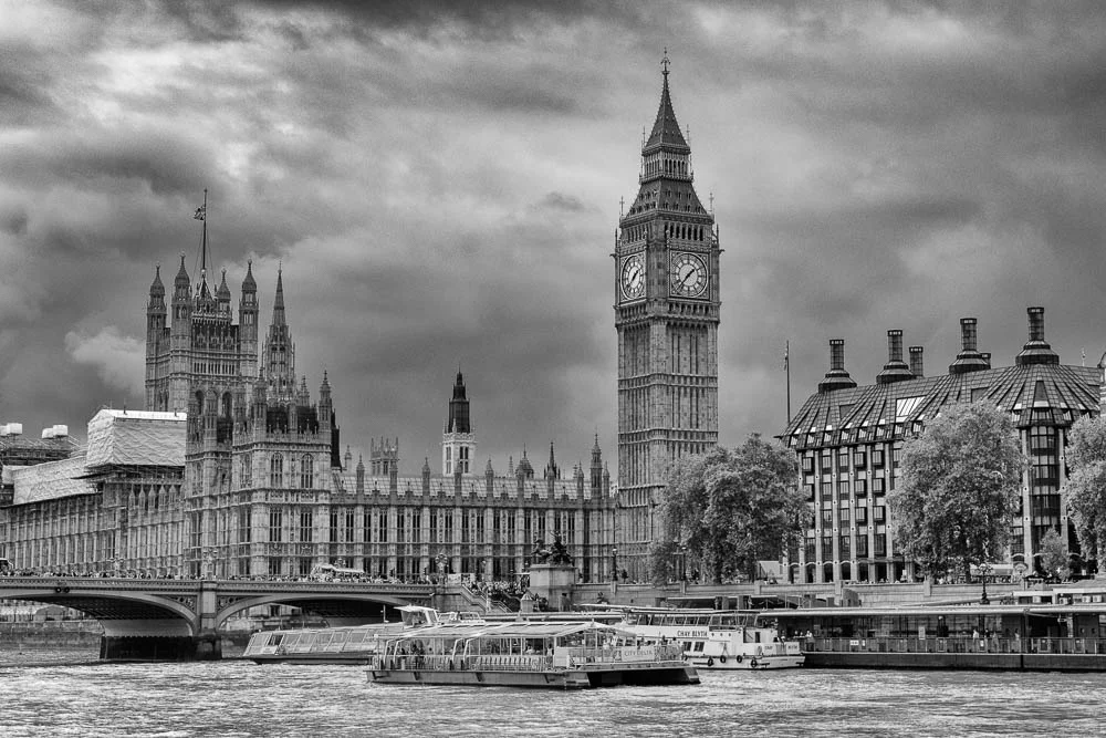 Westminster Palace mit dem Elizabeth Tower am Ufer der Themse in London als Schwarzweißaufnahme.