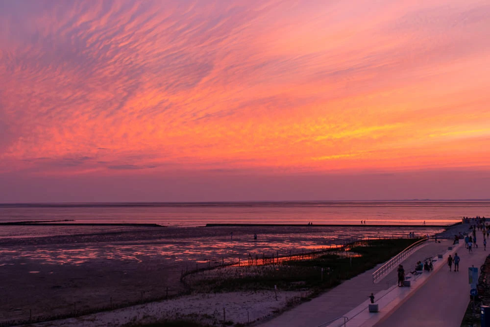 Sonnenuntergang über der Nordsee bei Norddeich mit farbenfrohem Abendhimmel und Blick auf den Deich.