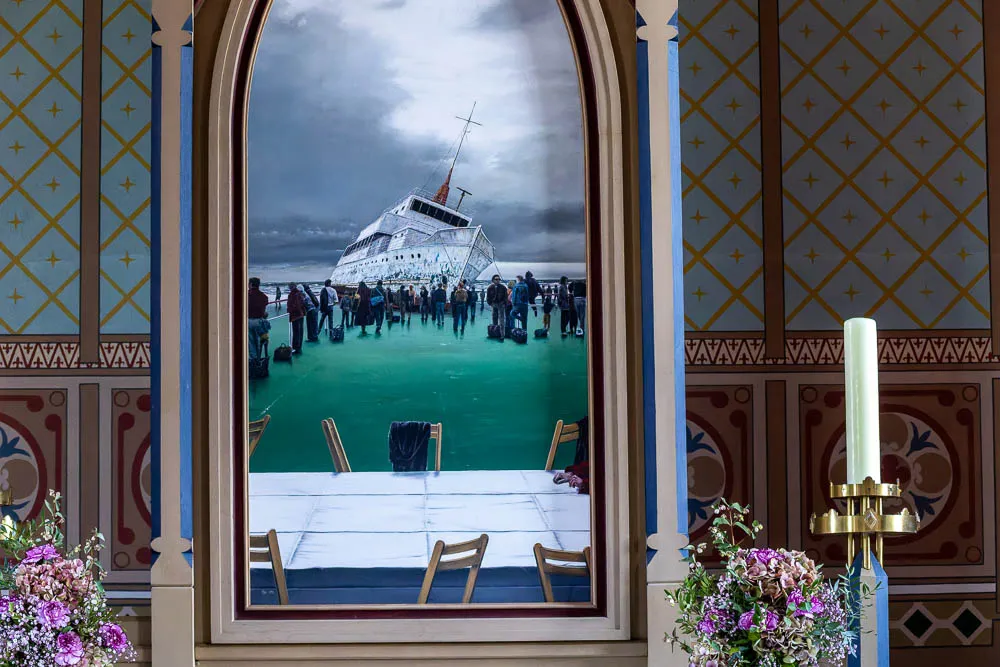 Das Altarbild von Hermann Buß in der Inselkirche Langeoog zeigt ein gestrandetes Schiff und Menschen am Strand.