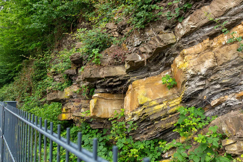 Ein geologischer Aufschluss mit unterschiedlich gefärbten und geschichteten Gesteinslagen am Hengsteysee.