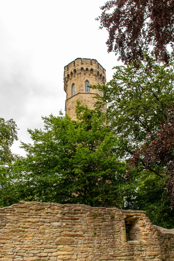 Der Bergfried der Hohensyburg ragt hinter den erhaltenen Mauern der Burgruine aus den Bäumen.