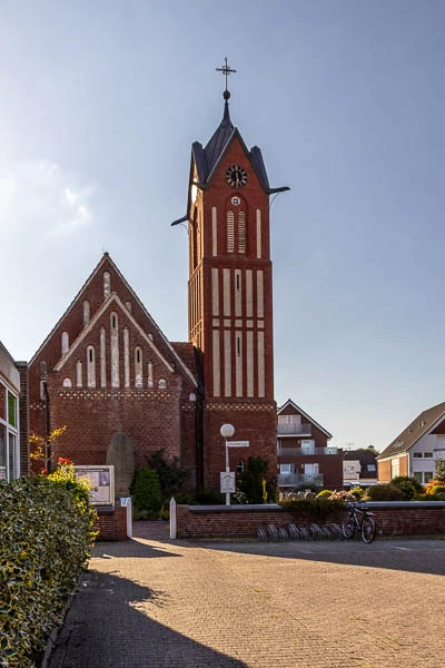 Die Inselkirche von Langeoog mit ihrem markanten roten Kirchturm an einem sonnigen Tag.