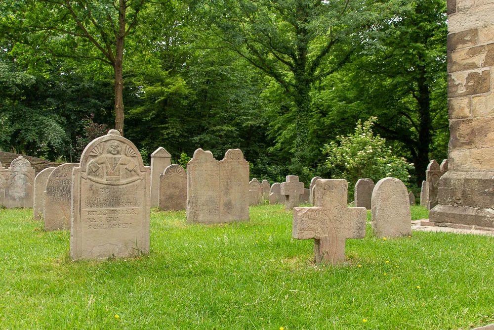 Historische Grabsteine stehen dicht an dicht auf dem Kirchhof von St. Peter in Syburg.