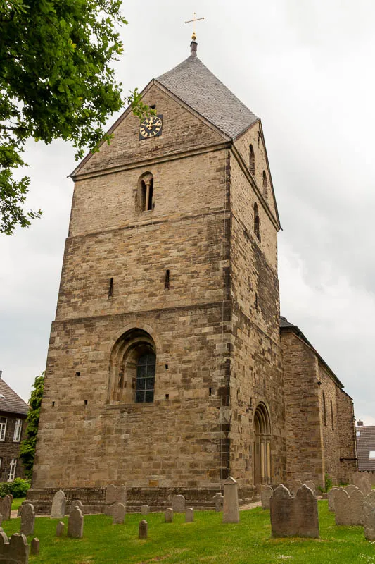 Die romanische Kirche St. Peter in Syburg steht mit ihrem markanten Turm auf einem historischen Kirchhof.