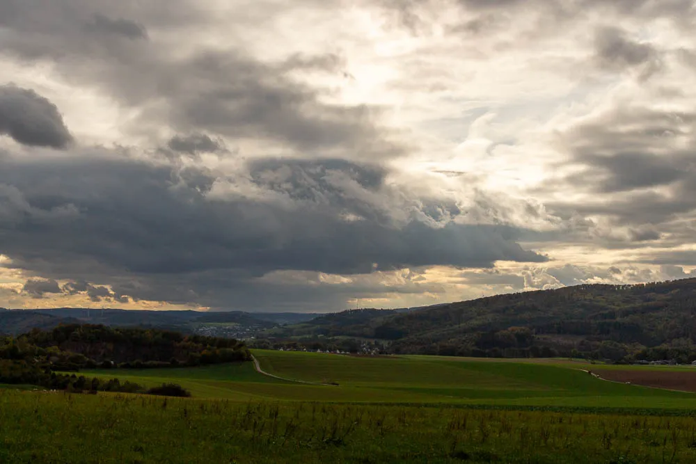 Dunkle Wolken ziehen über die Felder und bewaldeten Hügel bei Eisborn.